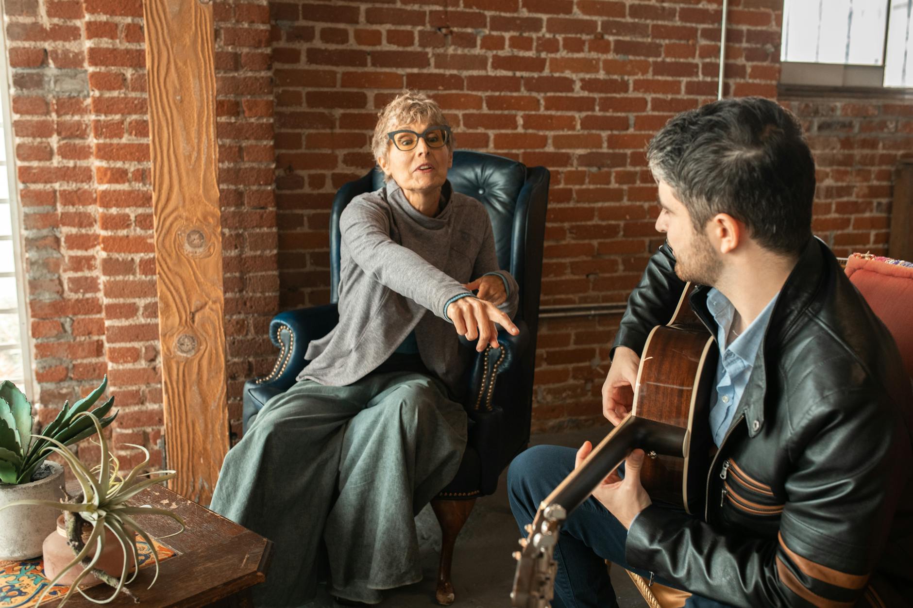 Homme En Pull Bleu Assis Sur Un Fauteuil En Cuir Marron