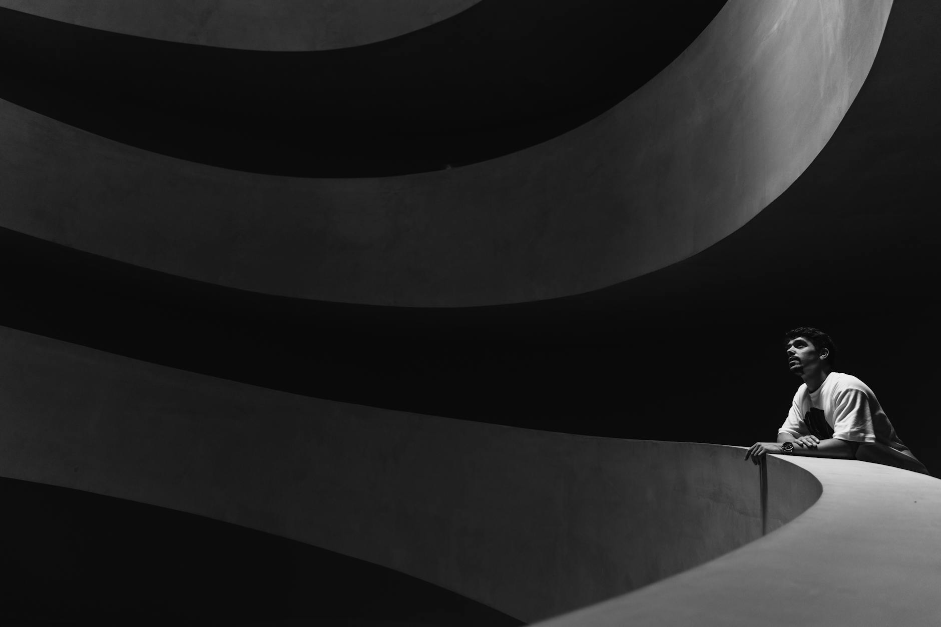 Photo minimaliste en noir et blanc d'un homme dans une architecture moderne.